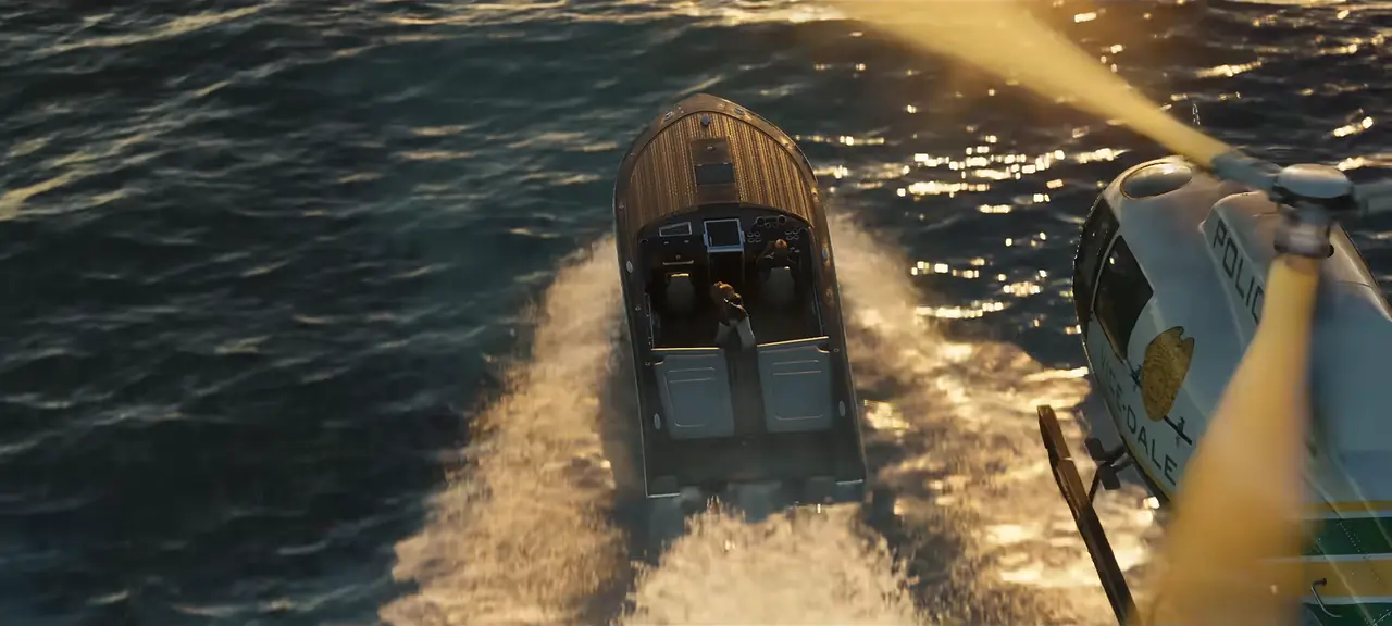 A police helicopter chasing a wooden speedboat across the water, seen from above