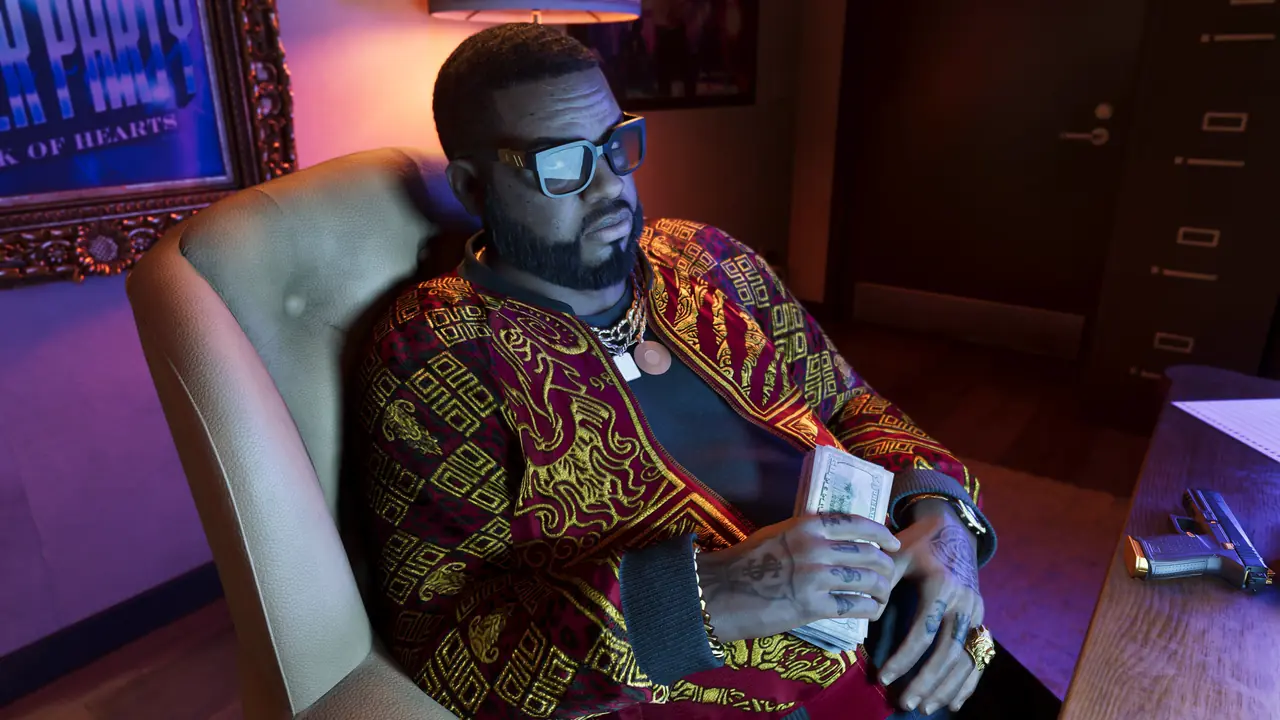 Boobie Ike in sunglasses and a patterned shirt, sitting in a leather office chair holding a stack of cash