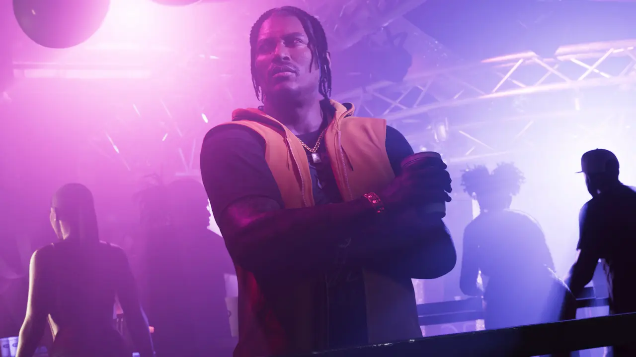 Dre'Quan Priest with arms crossed in an orange vest, standing in a purple-lit nightclub