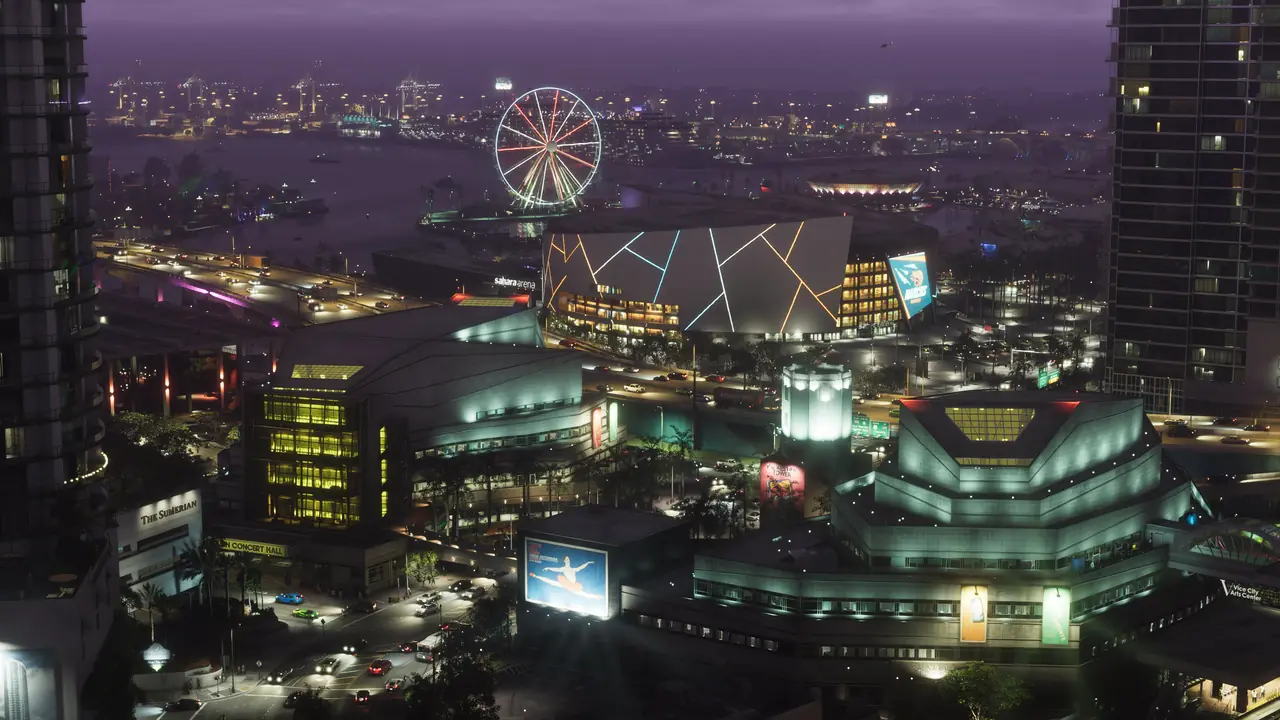 Vice City at dusk from above, with lit towers, a Ferris wheel and a neon-lit arena